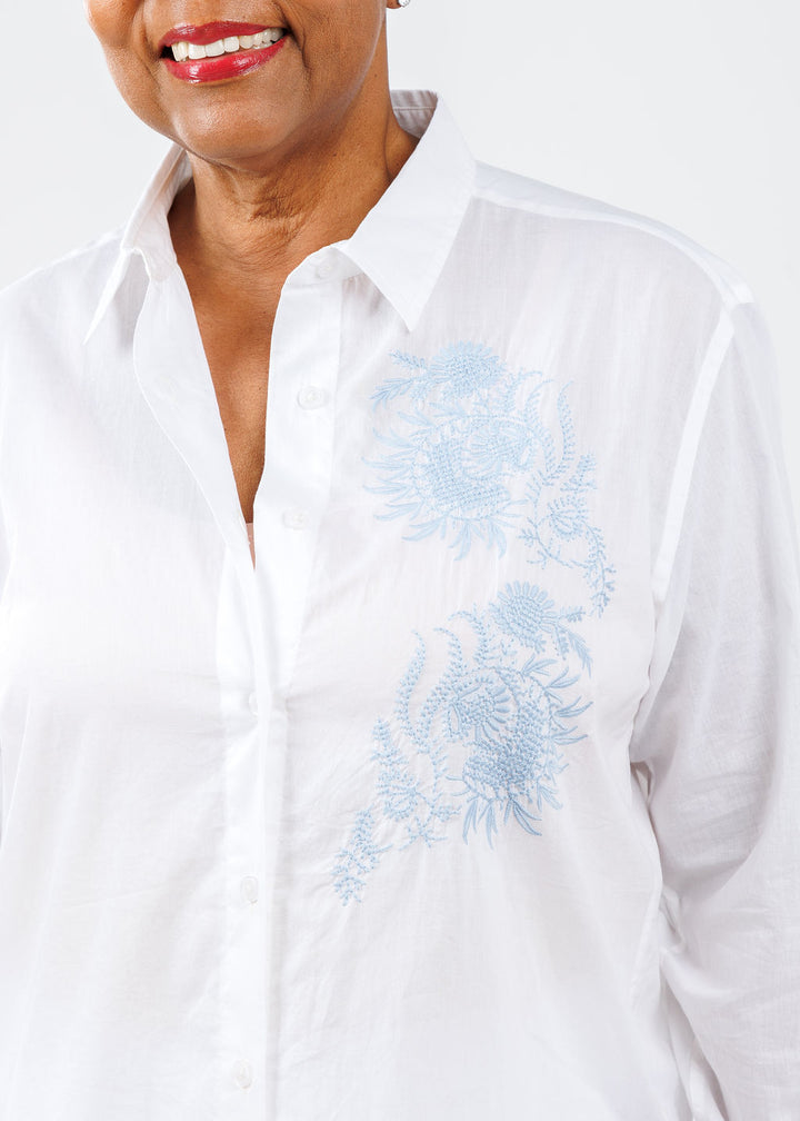 White shirt with blue embroidery worn by a person on a white background